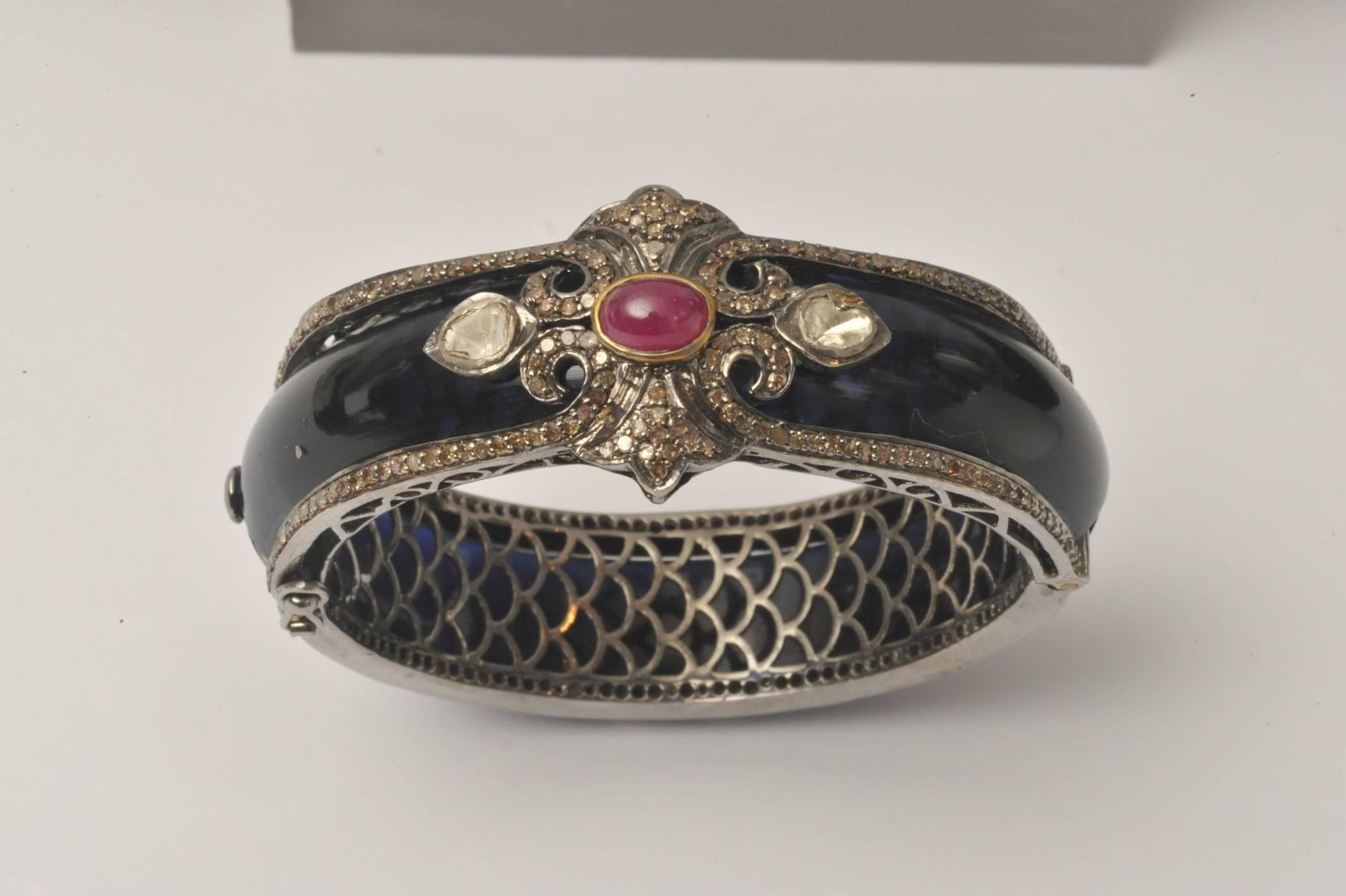 This is a regal modern Bakelite bracelet bordered with pave` set diamonds, rosecut diamonds on the top and a cabochon ruby at the center, all set in oxidized sterling.   A push clasp with double safeties at the side.  Sits close to the
