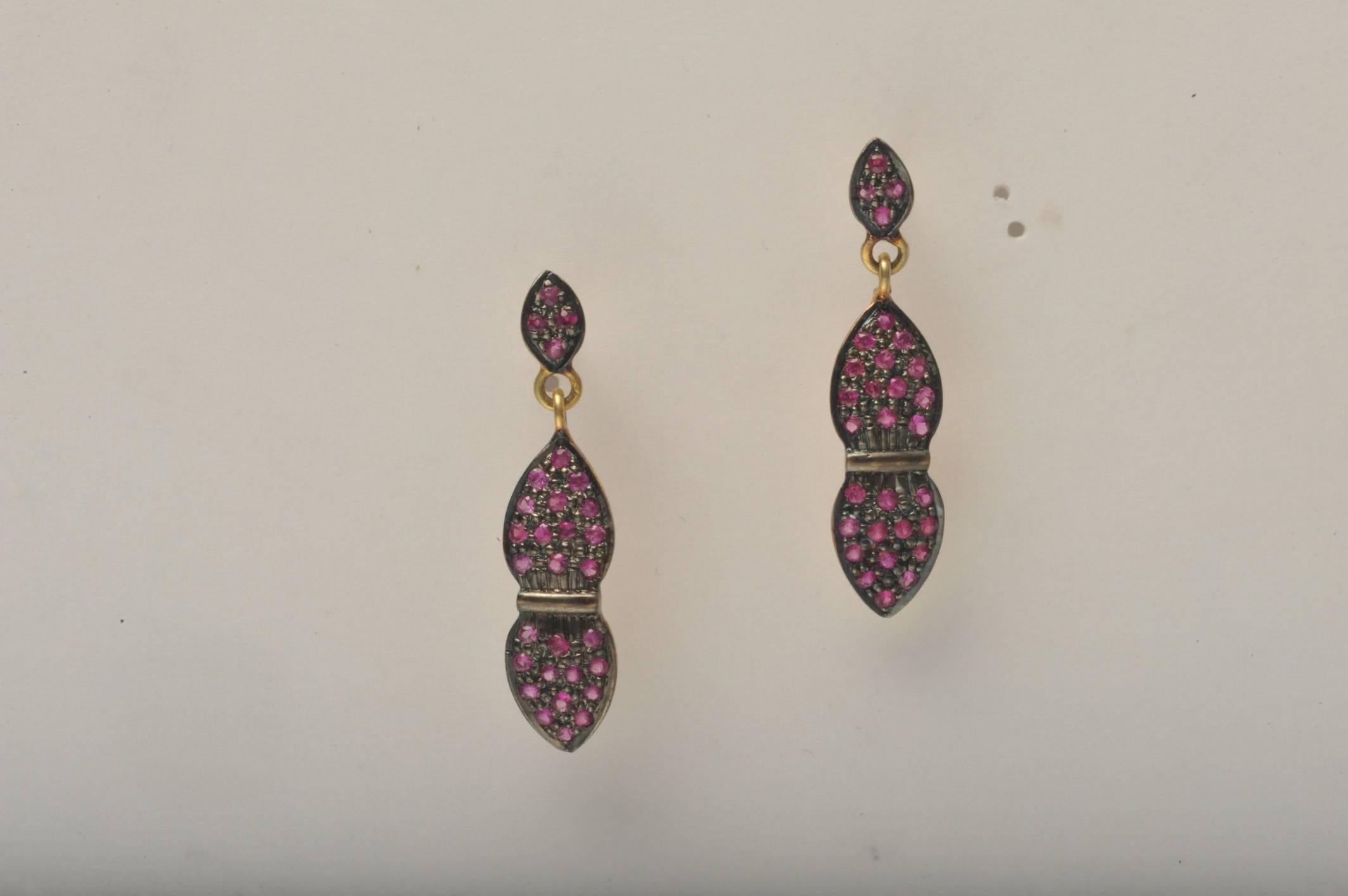 A delicate pair of pave`-set faceted rubies, hinged in the middle and set in oxidized sterling silver with an 18K gold post.  Carat weight of rubies is .89.