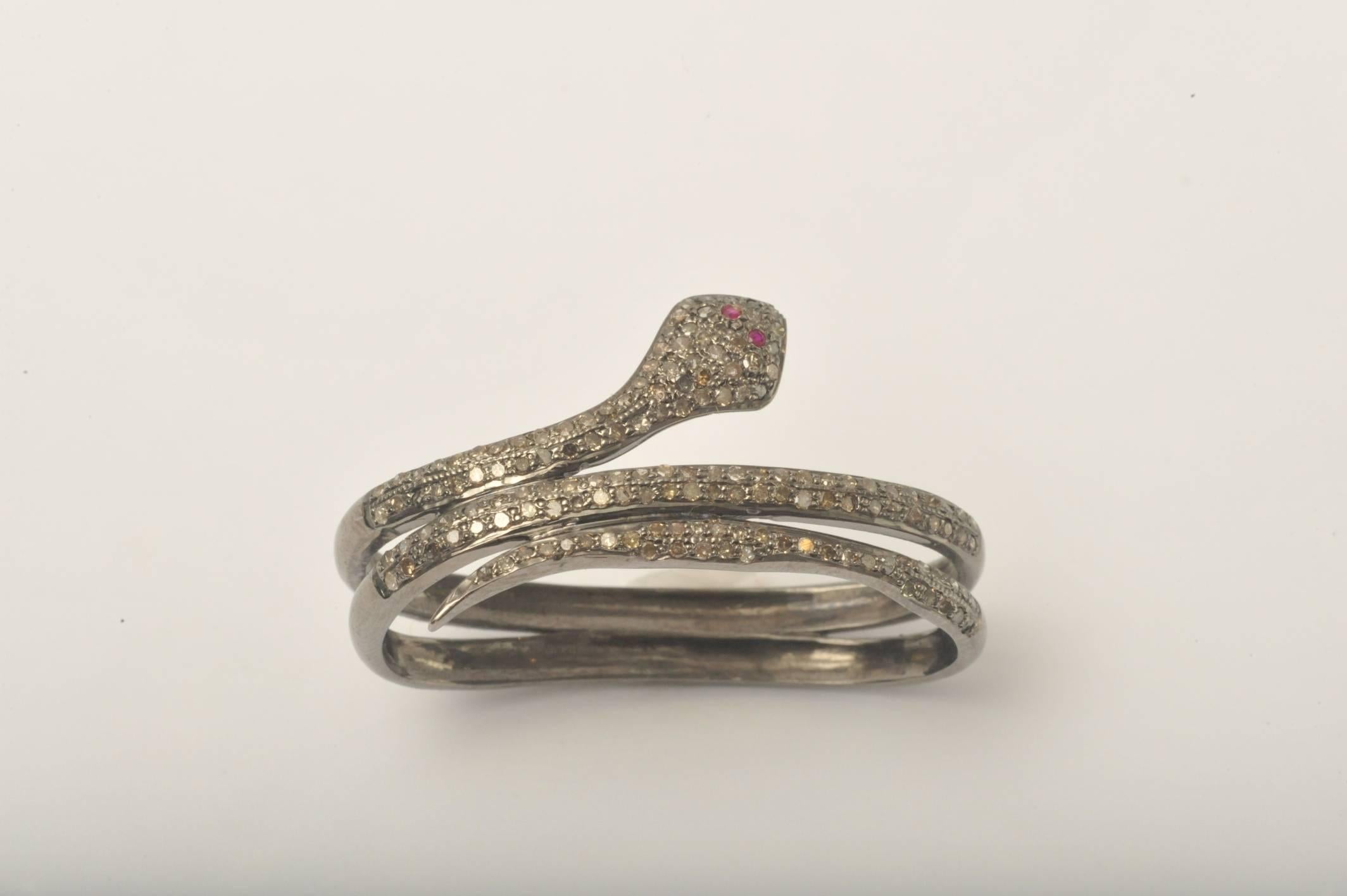 An ususual two-finger snake ring comprised of solitaire diamonds with ruby eyes set in oxidized sterling silver.  Actually quite comfortable, not using your index finger.  Inside measurement is 1.87 inches; by .75 inches.