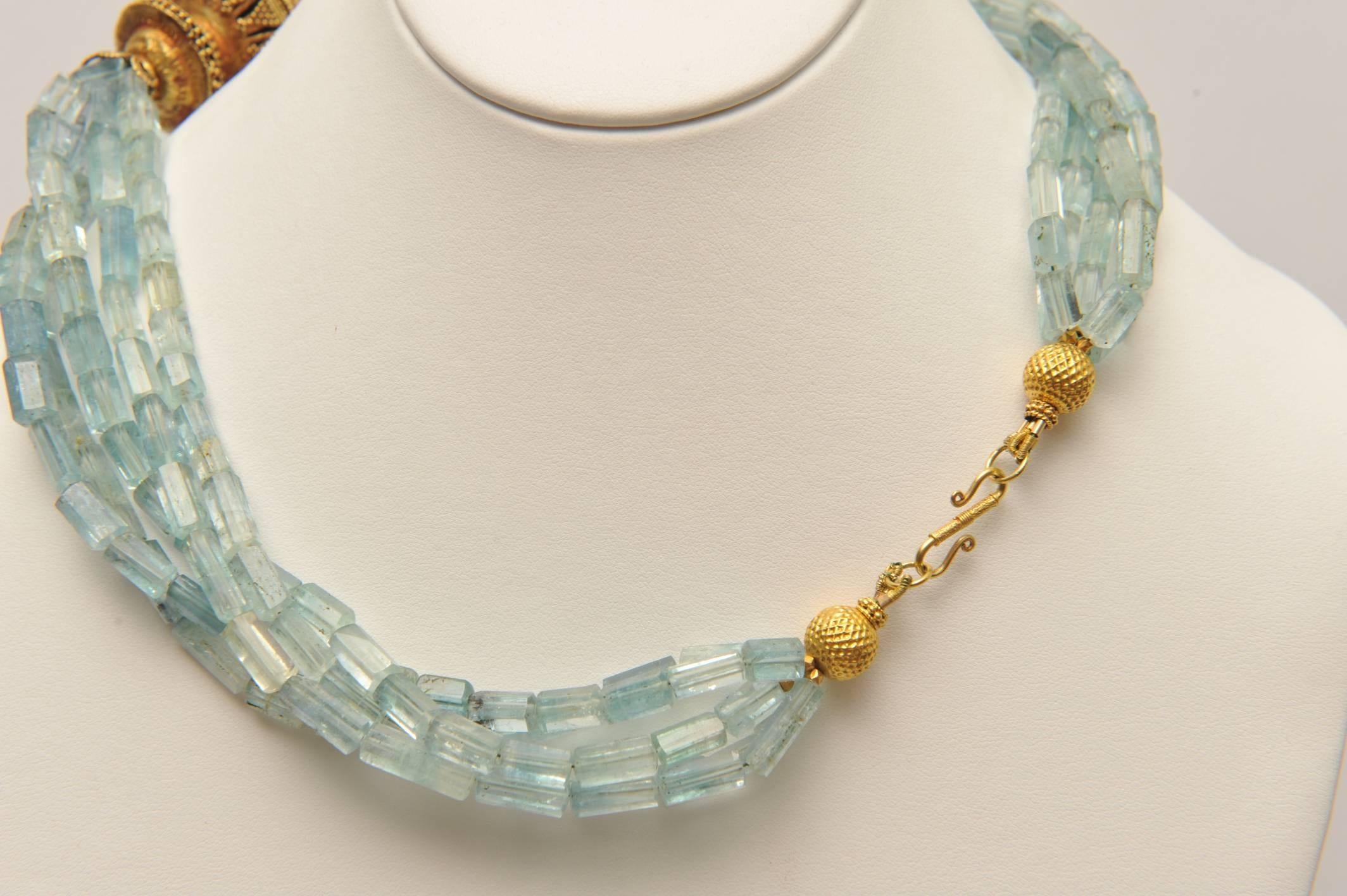 A rare and unusual multi-strand necklace comprised of faceted tubular shaped aquamarine beads with beautiful blue and green clarity, coupled with an exquisite old, 22K gold bead with fine granulation work and detail.  One of a kind designs by