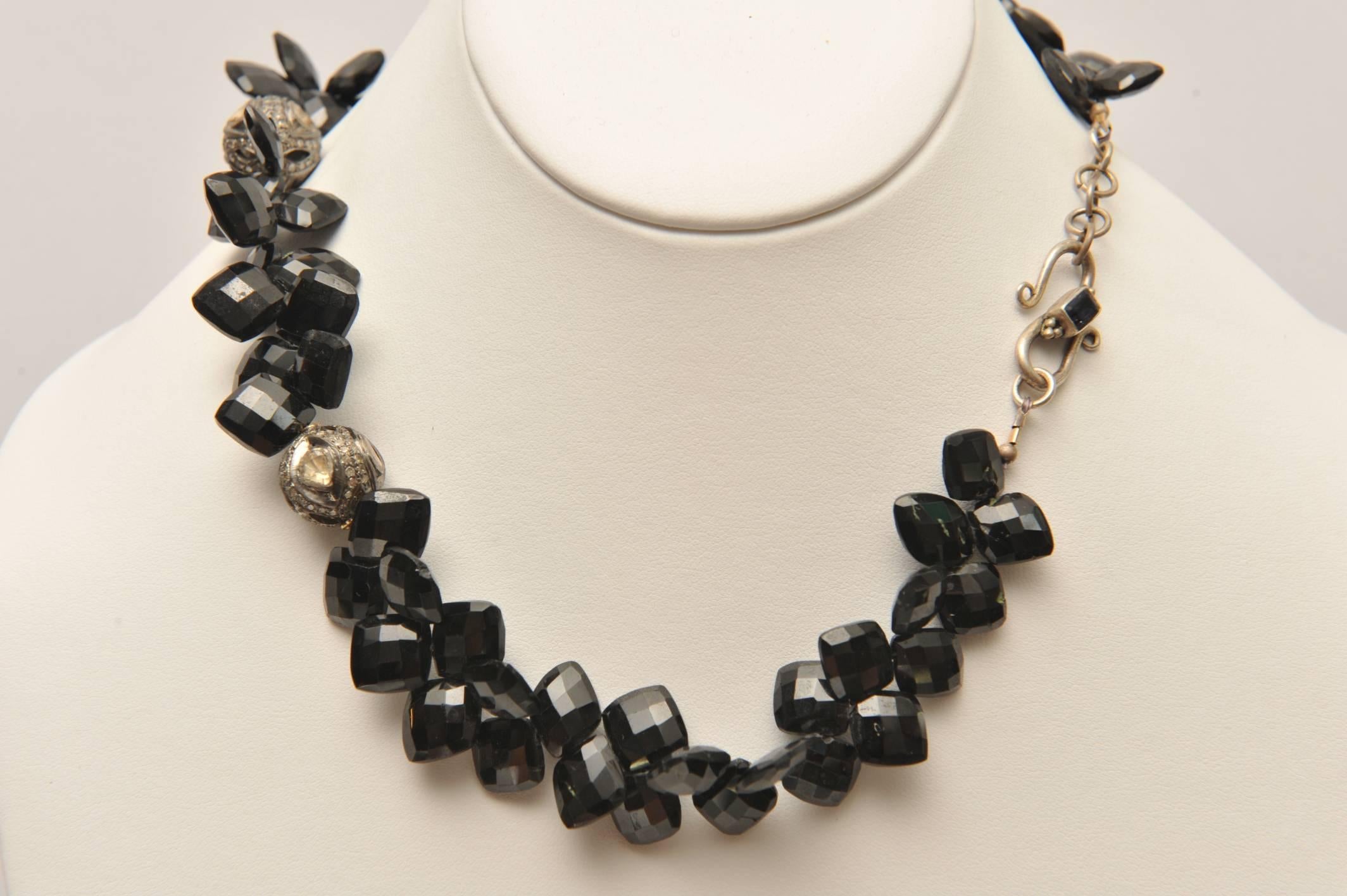 Very unusual cuts of black onyx--a faceted diamond shape with the beads drilled across the top.  These are paired with three rose cut and pave`-set diamond beads set in sterling silver.  Sterling clasp with a faceted sapphire and the one inch chain