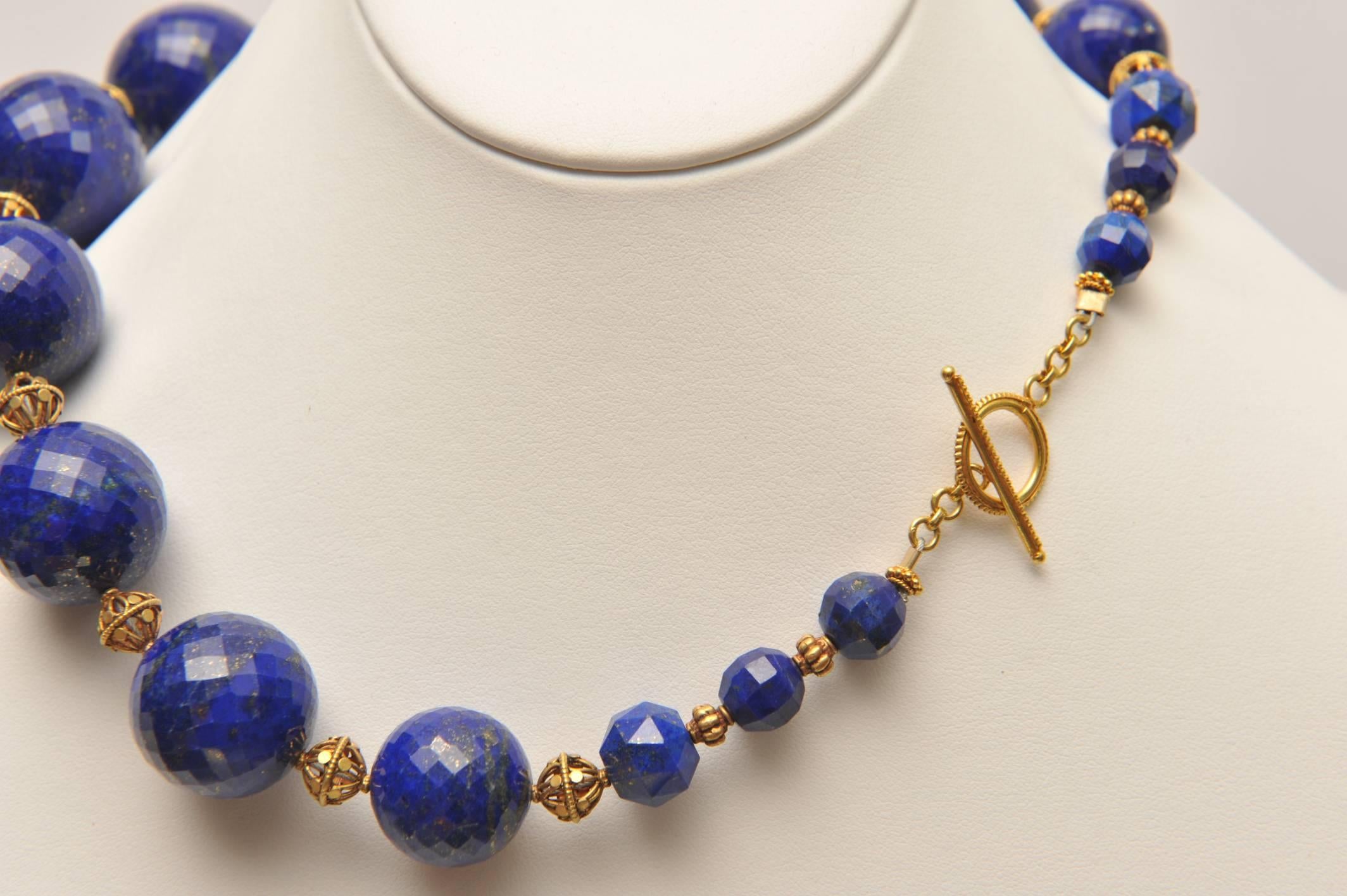 A graduated strand of beautiful and rare peacock blue faceted lapis lazuli beads with 18K gold open-work beads in between, with toggle clasp.  Very rare and unusual to find this color, size and finely faceted lapis lazuli.  The largest center bead