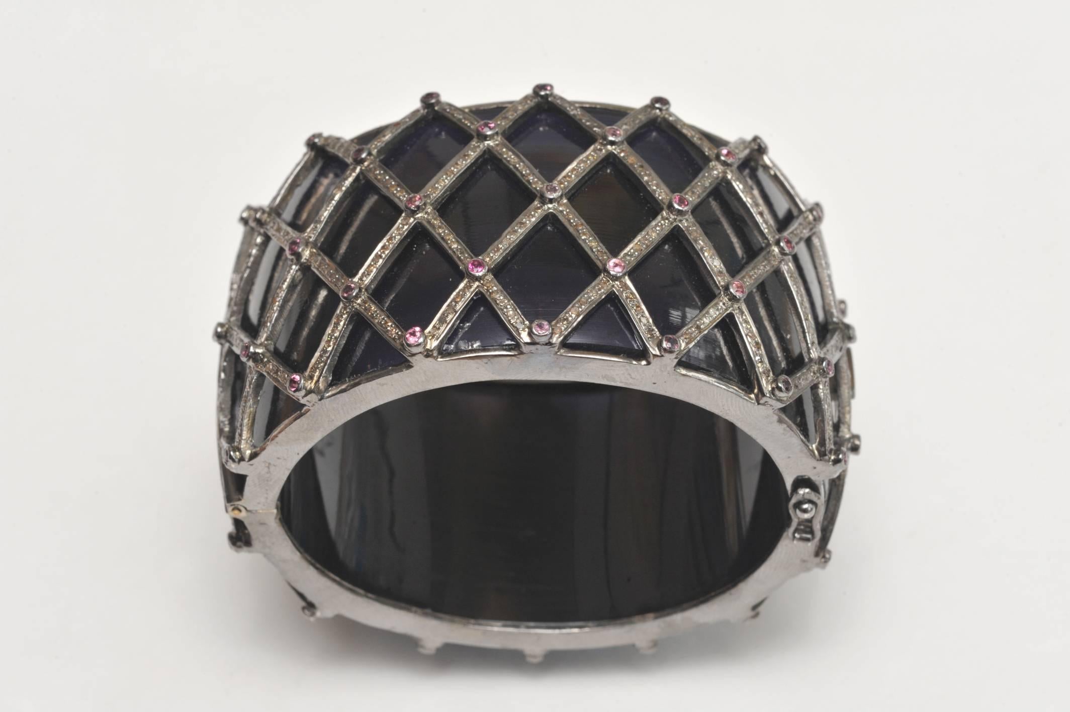 Unusual black enamel, hinged cuff bracelet in sterling silver with faceted rubies and pave` set diamonds.   4.94 ct of diamonds, 2.40 ct of rubies.  Cross hatch design covers entire bracelet, push clasp with safety catches.  Interior circumference