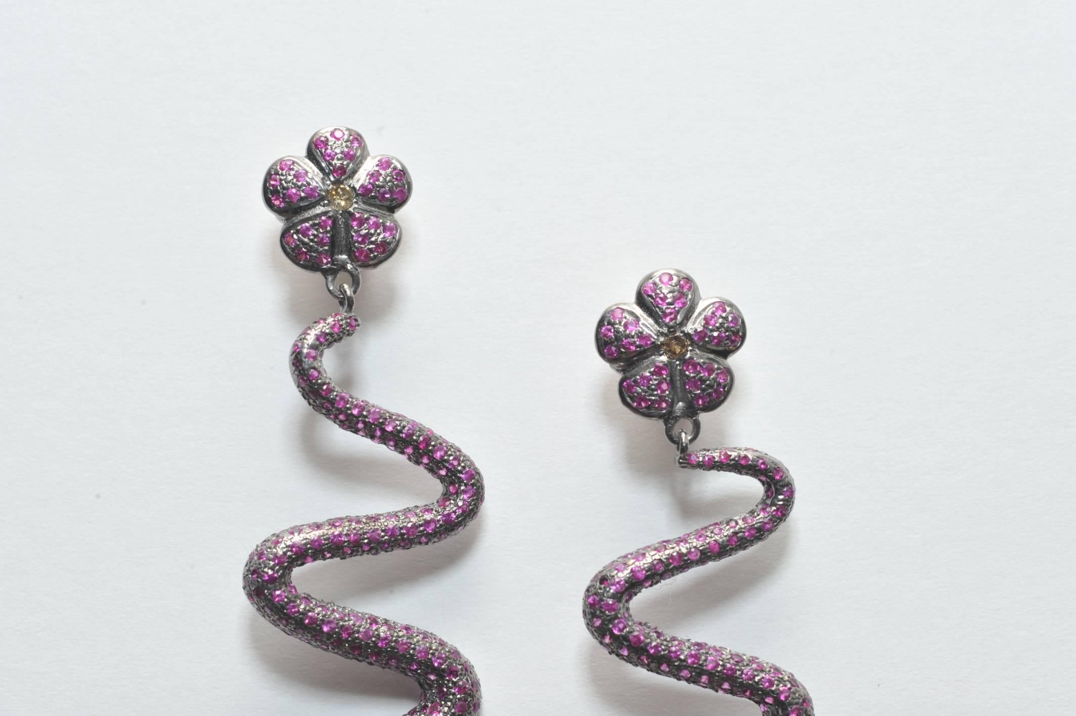 A fabulous pair of pave`-set ruby snake earrings in oxidized sterling silver with 18K gold post and diamond eyes.  Ruby carat weight is 5.55, diamonds .11.
