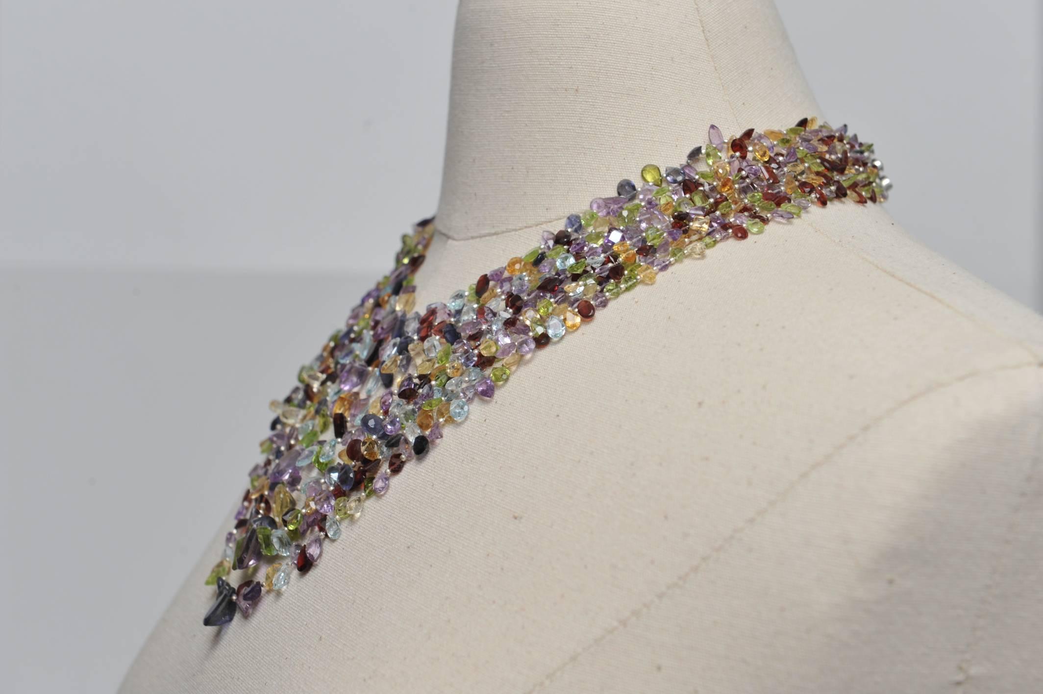 This exceptional necklace consists of nine strands of faceted semi-precious stones of various cuts, shapes and sizes.  The stones are aquamarine, citrine, peridot, amethyst, garnet, and iolite.  There are emerald cuts, marquise, pear, ovals and