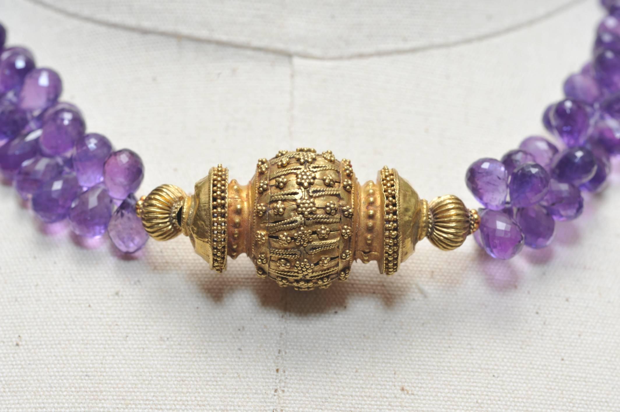 A rare, old 22K gold Indian centerpiece bead with fine granulation work strung with a cluster of fine quality and color, faceted amethyst briolettes.  Just the gold portion of the necklace measures 2.25 inches long x .875 inches wide.