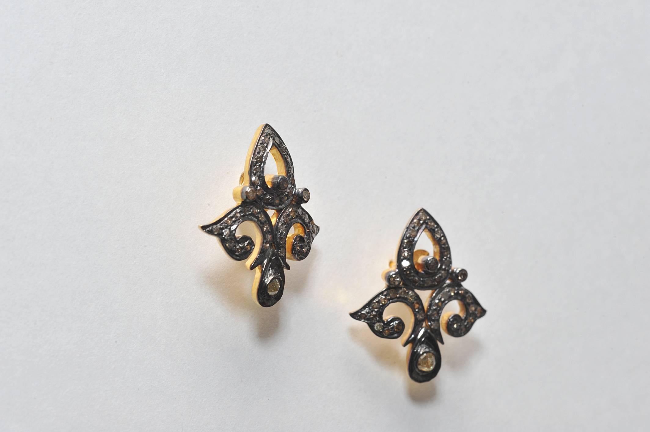 Diamants sertis dans de l'argent sterling oxydé, dans un design classique de fleur de lys, avec une tige en or 18 carats pour oreilles percées.  Le poids du carat est de .87.