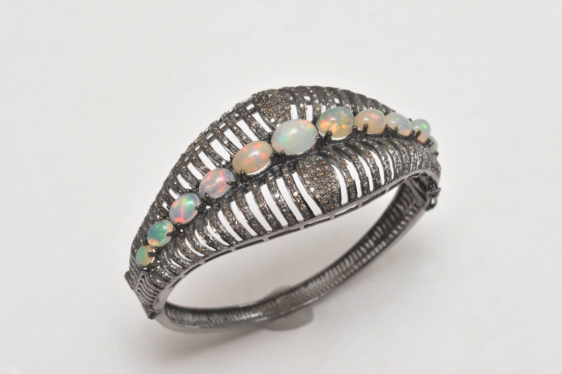 Incredibly fiery opals among pave`set diamonds in an oxidized sterling bracelet.    Oval shape keeps the stones on top of the wrist.  Push clasp with two side safeties.  Inside circumference is 6.5