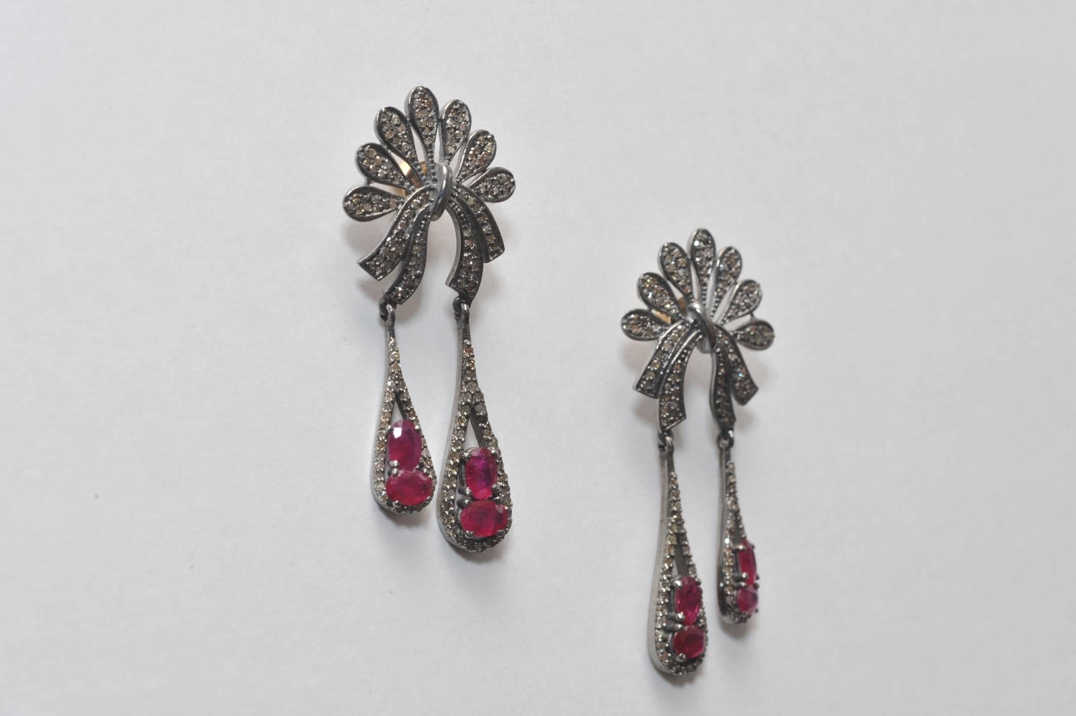 Very unusually shaped post of pave`-set diamonds with two dangles of diamonds and faceted oval shaped rubies.  Set in an oxidized sterling silver, with 18K gold post for pierced ears.  Diamond weights are 2.64 carats and rubies are 4.90 carats.

