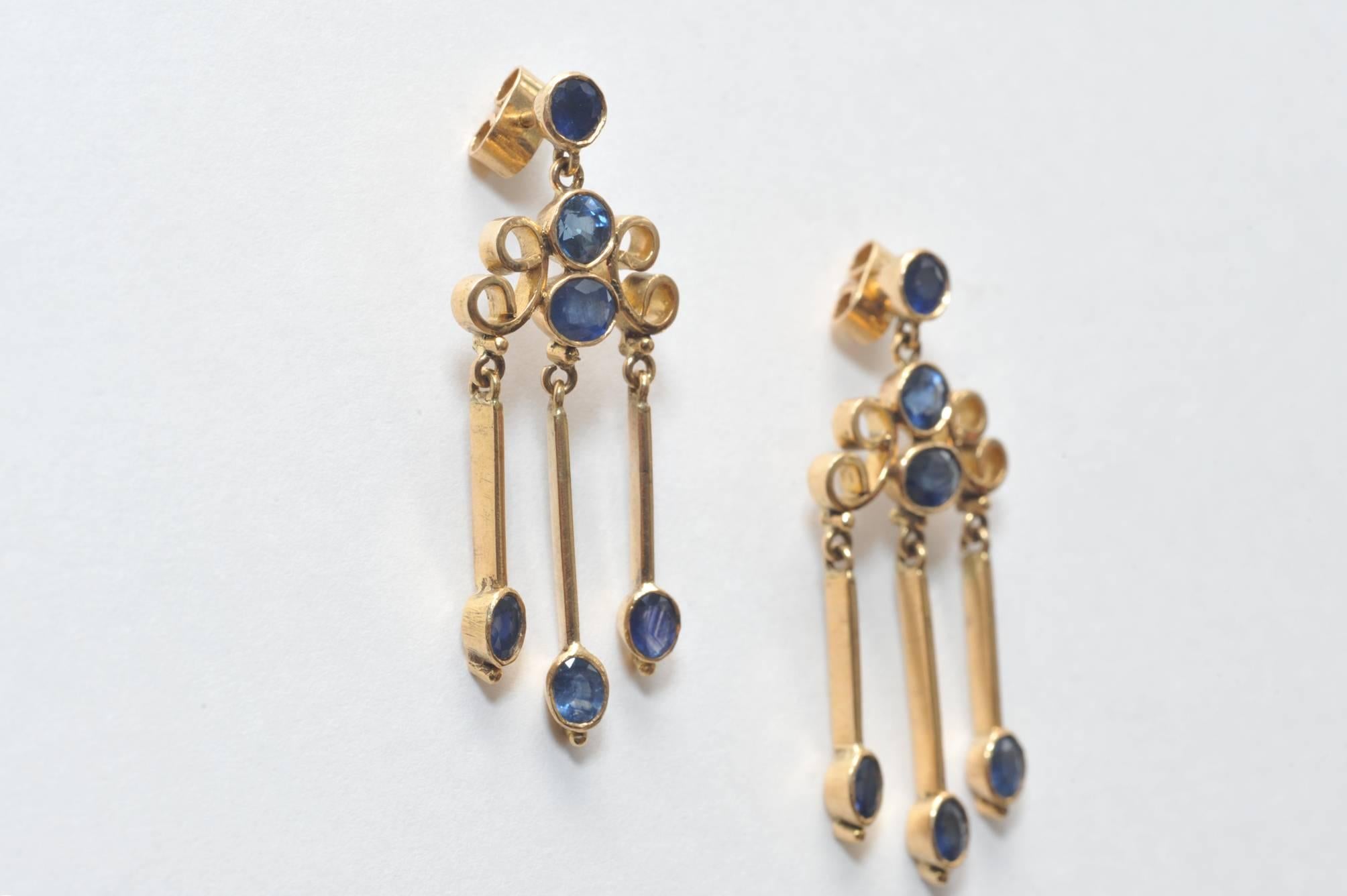 Pair of art deco period dangle earrings of 18K gold with faceted blue sapphires for pierced ears.  3.50 carats of sapphires.