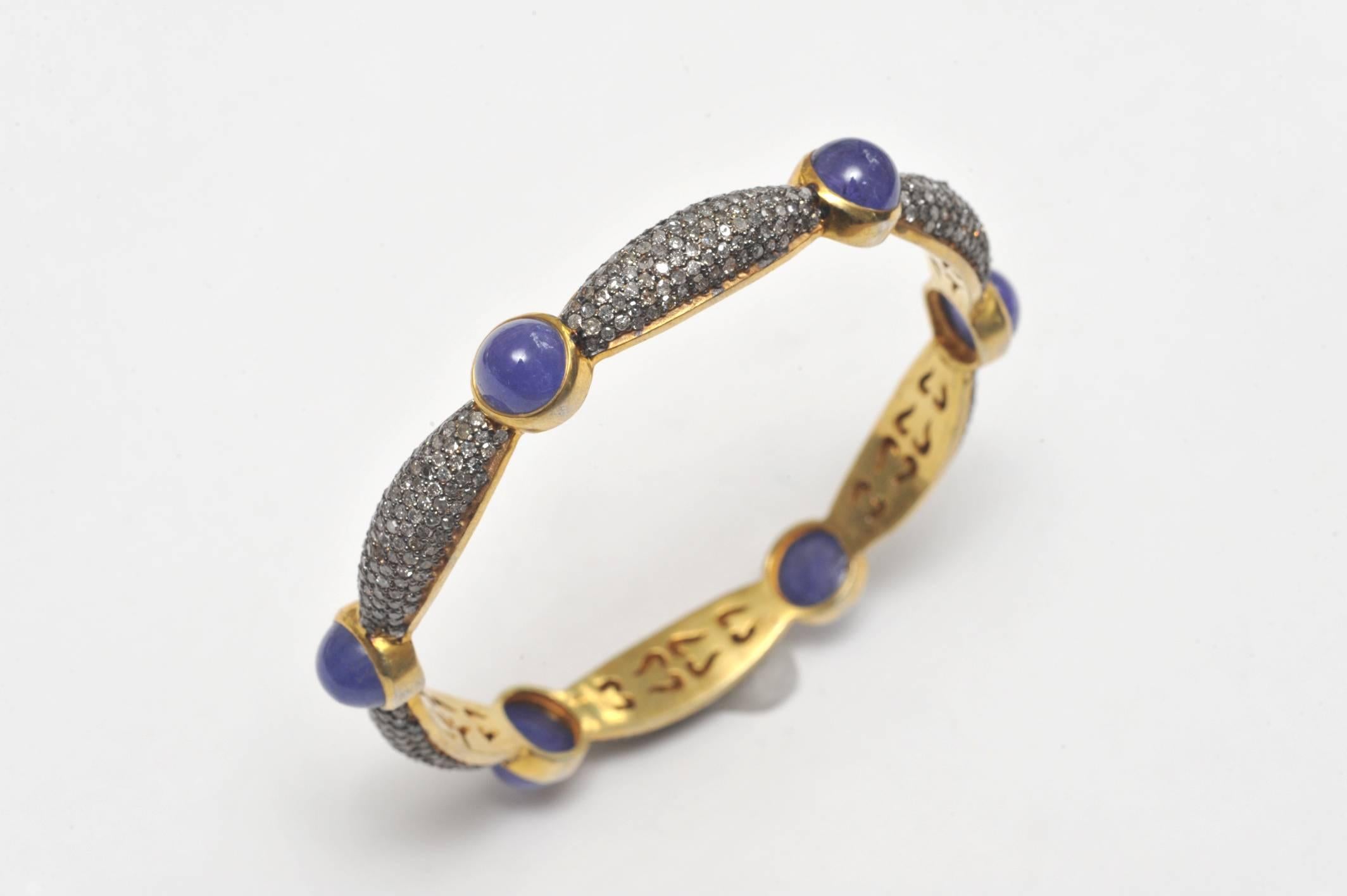 Bangle of cabochon Tanzanites mounted between settings of domed pave` diamonds in sterling.  The bracelet borders in 18K Gold.  Inside circumference is 7.5 inches.;  Tanzanite carat weight is 24.90; diamonds are 7.13 carats.