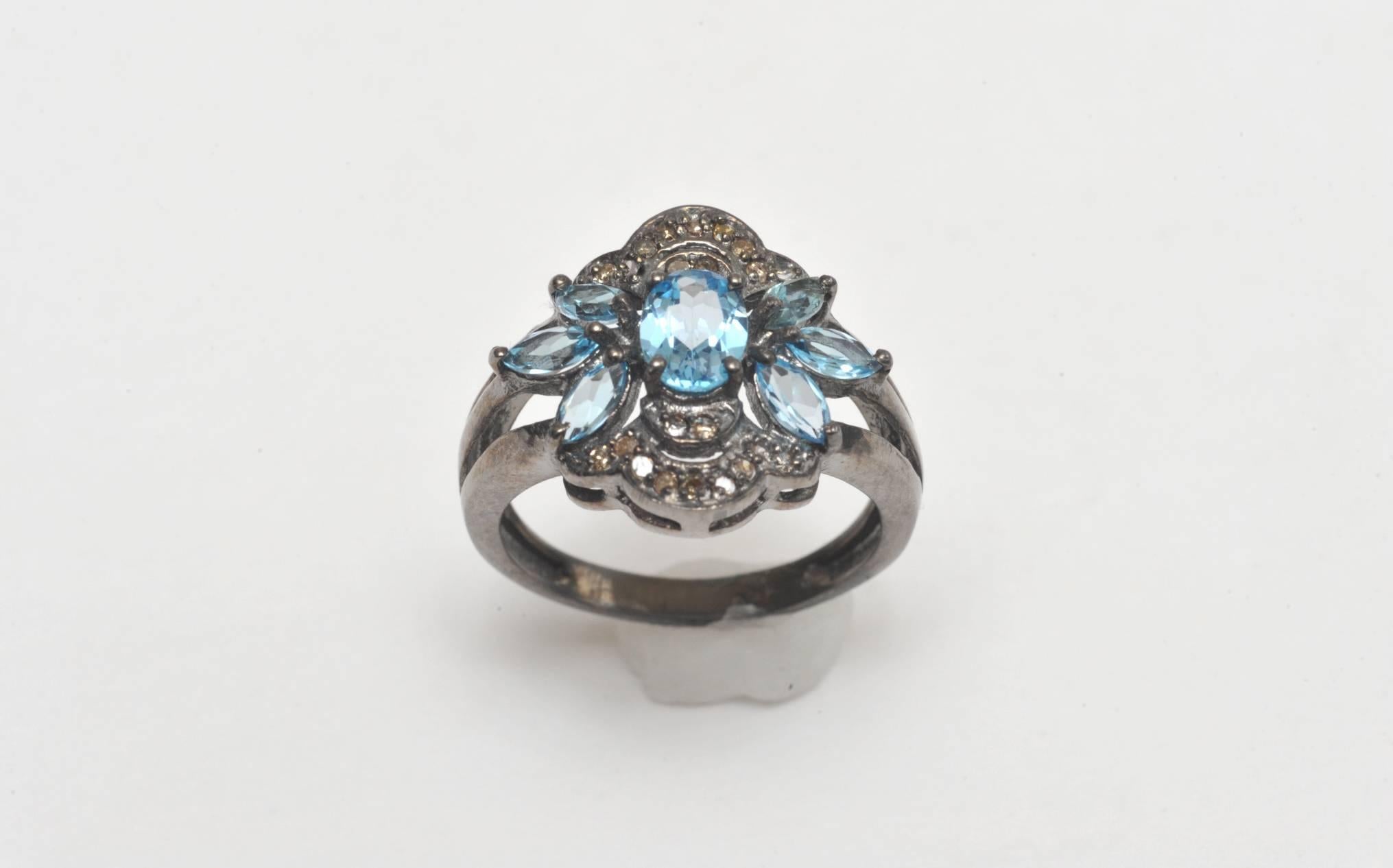 Faceted oval and marquise blue topaz stones set among pave`-set diamonds in oxidized sterling silver.  Ring size is 8.  Carat weight of blue topaz is 1.93 and diamonds are .19.