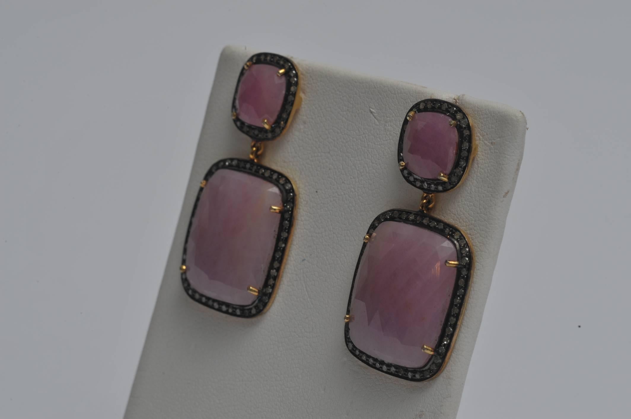 Unusual faceted pink sapphire slices bordered in pave`-set diamonds in oxidized sterling silver.  The posts are 18K gold for pierced ears.  Carat weight of pink sapphires is 43.13; carat weight of diamonds is .96.  The top portion of the earring