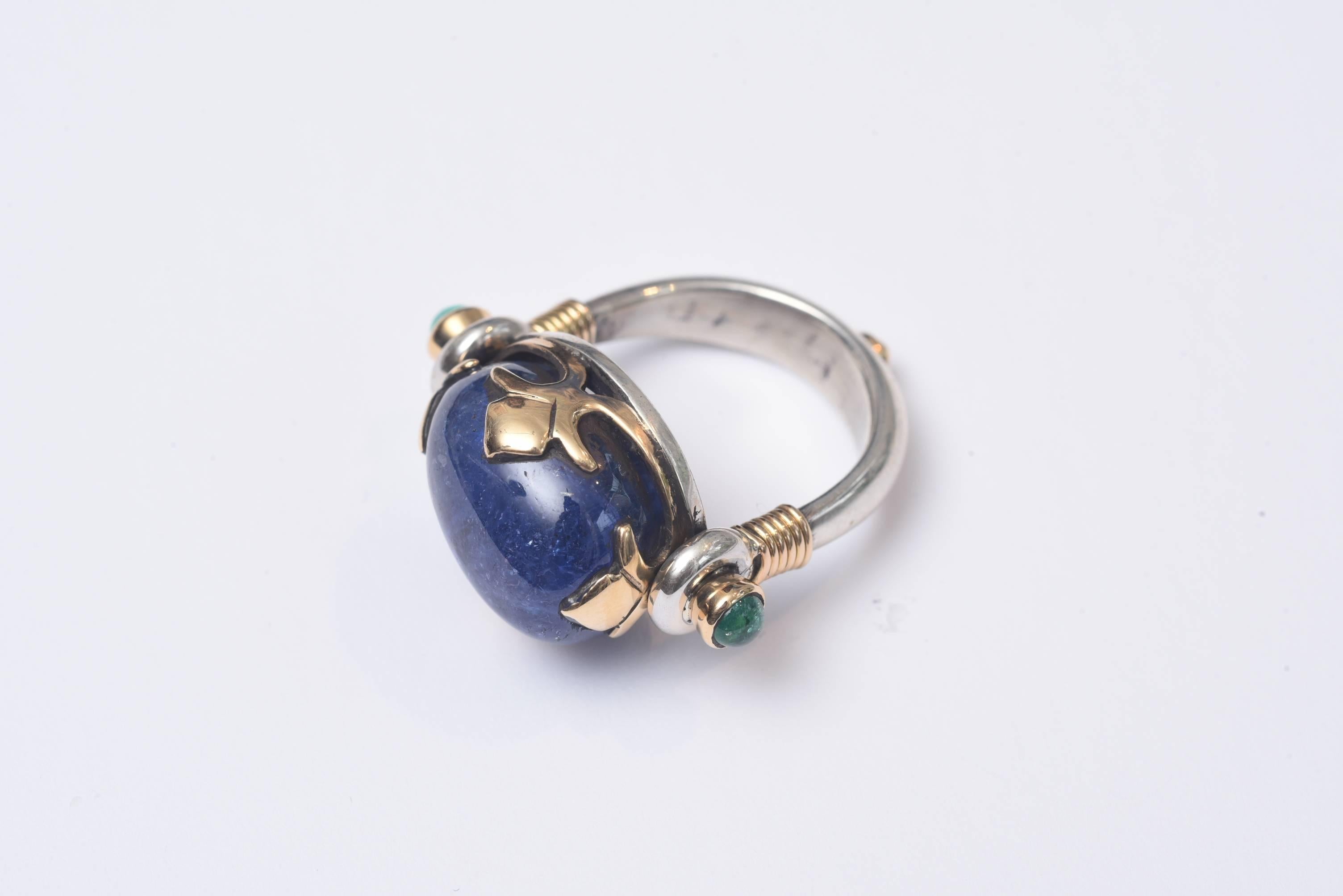 Lovely and unusual large cabochon sapphire set in 18K gold (not plated) with two emeralds at the sides and band is sterling silver.  Interesting and unusual gold fleur de lis bezel setting.  The sapphire portion measures .75 inches x .50 inches. 