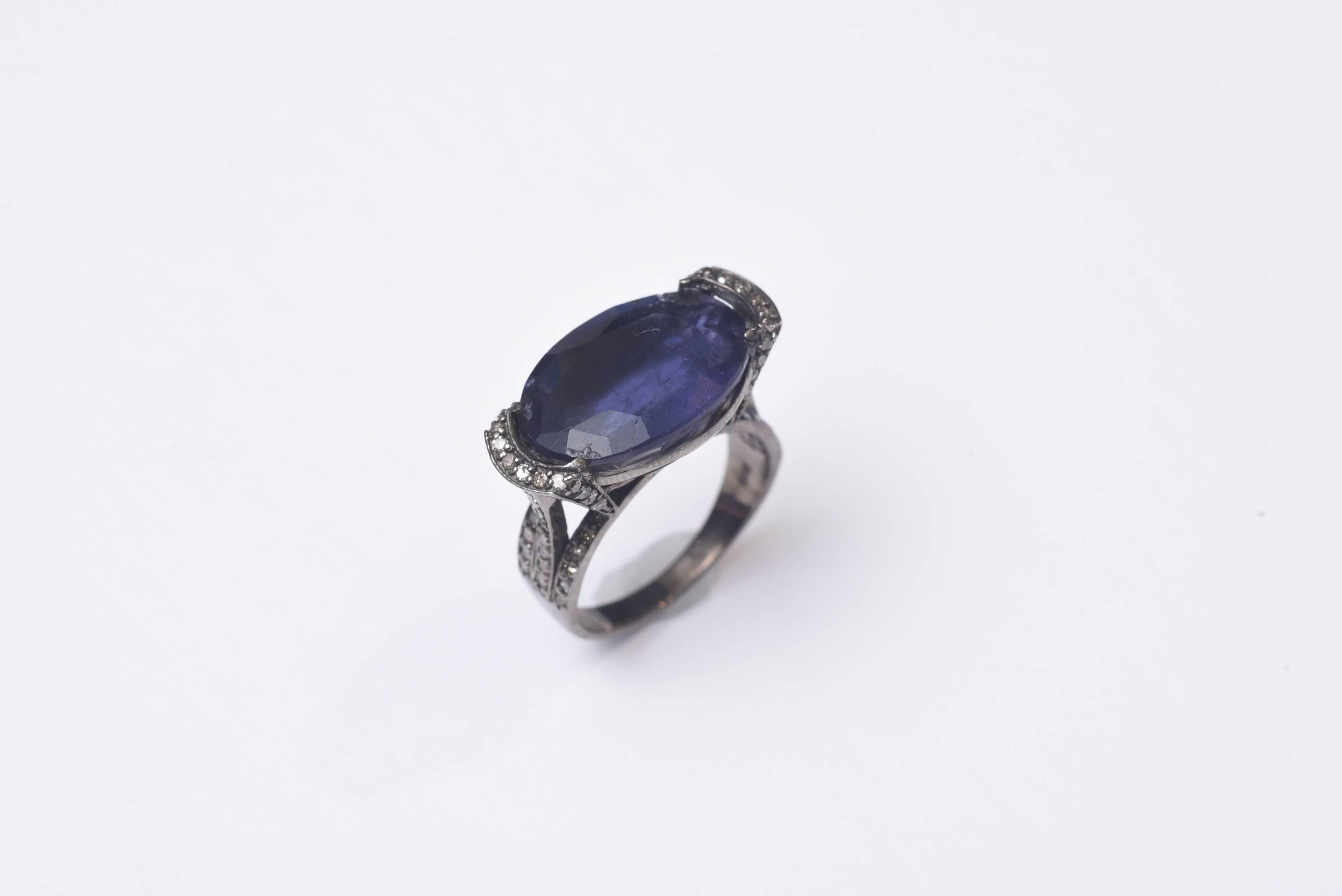 Large faceted iolite ring with pave` set diamonds on the sides as well as along the sides of the prongs and top of the band. Set in oxidized sterling.  Carat weight of iolite is 10.60 diamonds are .56 carats.  Ring size is 7.75.