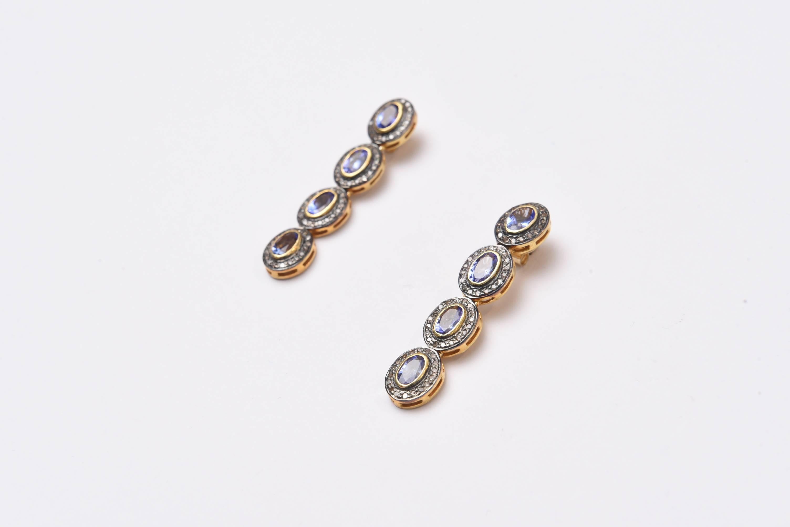 Four hinged, faceted oval tanzanite stones bordered in diamonds set in oxidized sterling silver.  18K gold post for pierced ears.  Carat weight of diamonds is 4.50 and tanzanites are 8 carats.
