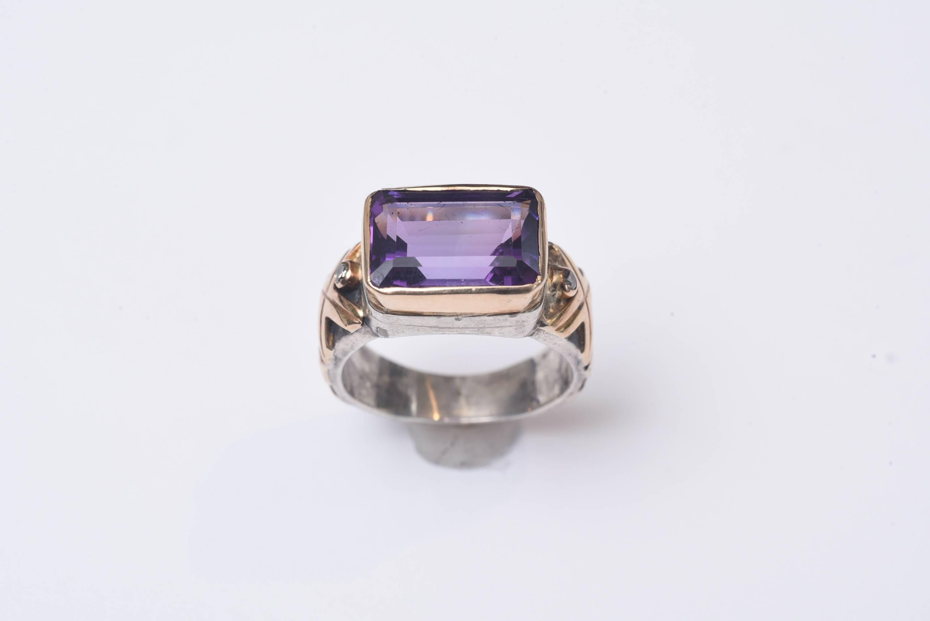 Emerald cut large amethyst set in 18K gold and sterling silver. flanked with two small faceted diamonds on each side. This is a weighted gold, not a gold plate. Gold work carries along the sides of the sterling band as well. Ring size is 8.25 Carat