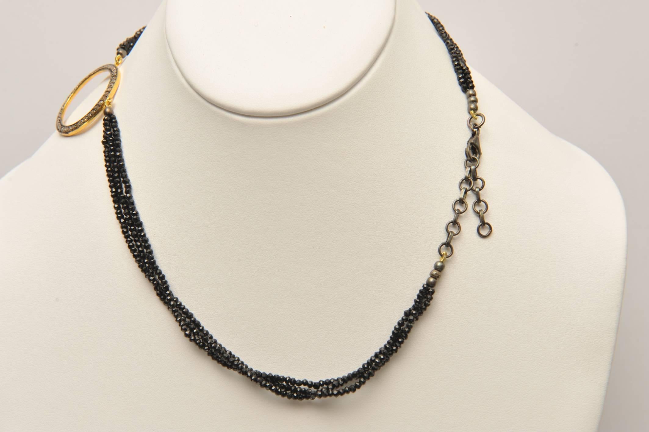 A pave` set diamond circle pendant in oxidized sterling silver with 18K vermeil on the backside , and three strands of faceted black spinel.  Chain across the back allows the length to range from 16 inches to 18 inches.

