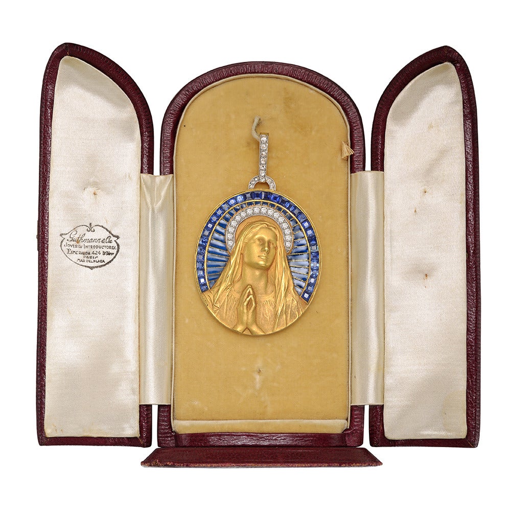 Madonna pendant, centering a finely carved depiction of the Madonna at prayer in 18k yellow gold, with diamond-set halo and surrounded by a semi-circle of plique-à-jour midnight blue vitreous enamel with the edge set with fitted blue sapphires, with