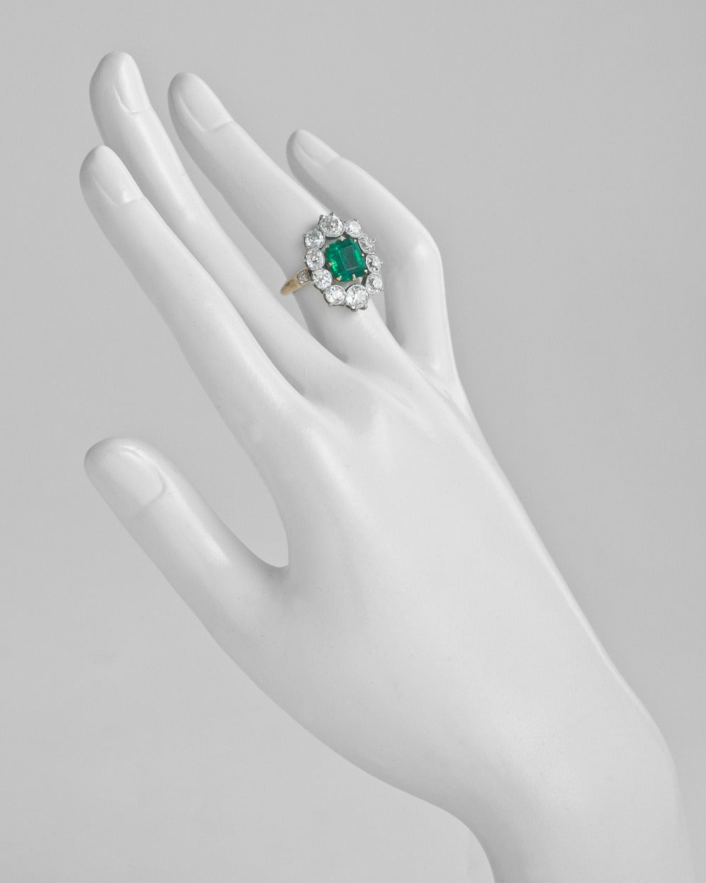 Victorian emerald and diamond cluster ring, centering on a natural square emerald-cut emerald weighing 2.20 carats (AGL-certified: of Colombian origin, non-treated), accented by a graduated old mine cut diamond surround with smaller old mine cut