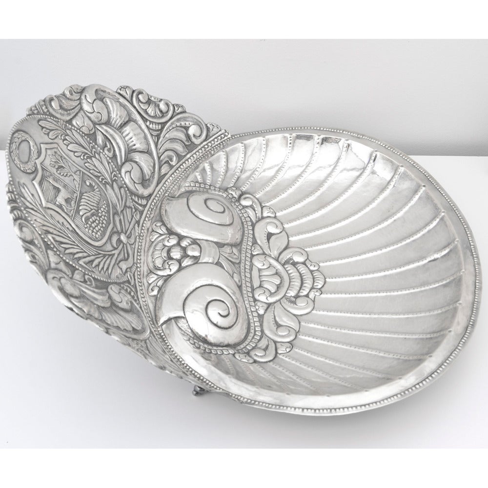 Large sterling silver wash basin, the bowl in a clam-shaped design, with top hood centering on a familial crest and spiral shell motif feet. Dimensions: 17.75
