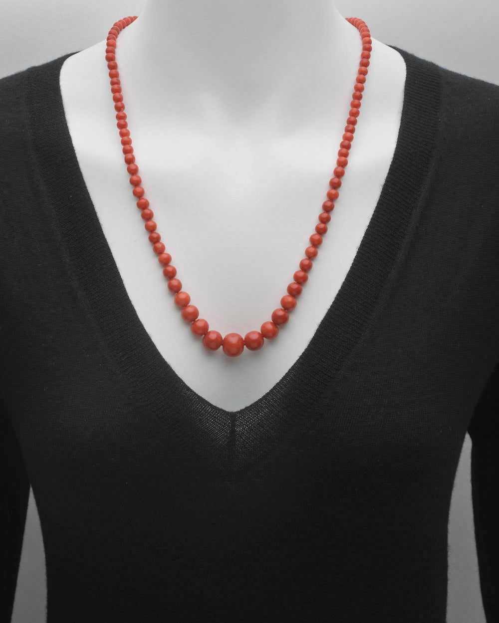 Red coral bead long necklace, designed as a graduated strand of coral beads ranging from 13.5mm to 4.5mm in diameter, secured by a navette-shaped clasp in 14k yellow gold. 28