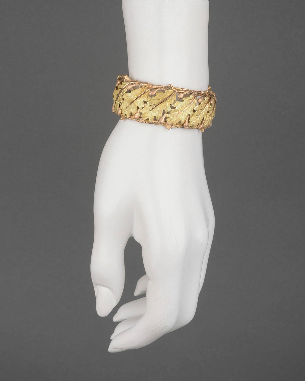 Oval-shaped, openwork oak leaf cuff bracelet, in hand-textured and engraved 18k yellow and pink gold, with hinge on one side, signed Mario Buccellati. 0.85