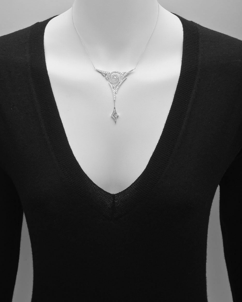 Diamond pendant necklace, designed as a 'V'-shaped pavé diamond pendant centering an open 'swirl' motif, with 99 round diamonds weighing approximately 1.50 total carats, mounted in 18k white gold, on a 16