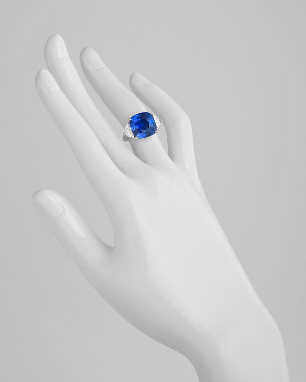 Ceylon sapphire and diamond ring, centering on a natural cushion-shaped sapphire weighing 10.59 carats, flanked by two near-colorless half moon-shaped diamonds, mounted in platinum. Accompanied by lab certificates from both the AGL and GRS for the