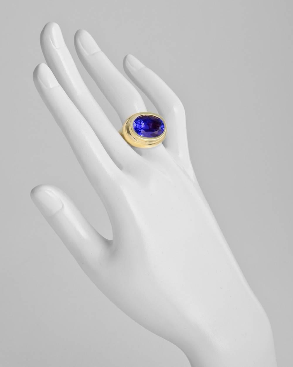 Dress ring, showcasing a bezel-set oval-shaped tanzanite weighing approximately 14.85 carats and measuring approximately 18 x 13mm from the top, mounted in 18k yellow gold. Size 8.5.
