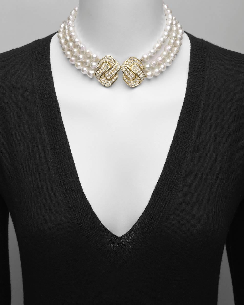 Baroque pearl collar necklace, designed with three strands of cultured baroque pearls measuring 8.5 to 9mm in diameter, strung on hand-knotted silk cord and secured by a stylized geometric knot-motif pavé diamond double clasp in 18k yellow gold.