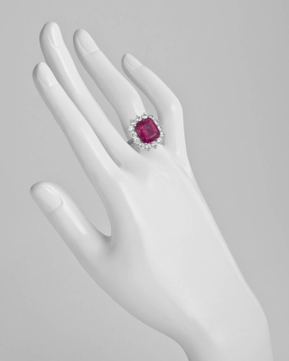 Rubellite and diamond cluster ring, centering a cushion-shaped rubellite weighing 6.99 carats, framed by a diamond surround composed of fourteen round-cut diamonds weighing 2.16 total carats, mounted in platinum. Size 6 (resizable to most ring