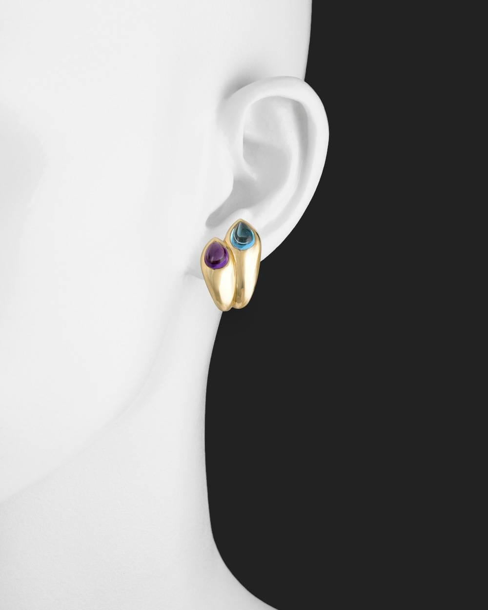 Gem-set earclips, showcasing twin pear-shaped cabochon blue topaz and amethyst, in polished 18k yellow gold, with clip backs, signed Bvlgari. Two amethysts weighing approximately 1.84 total carats and two blue topaz weighing approximately 2.44 total