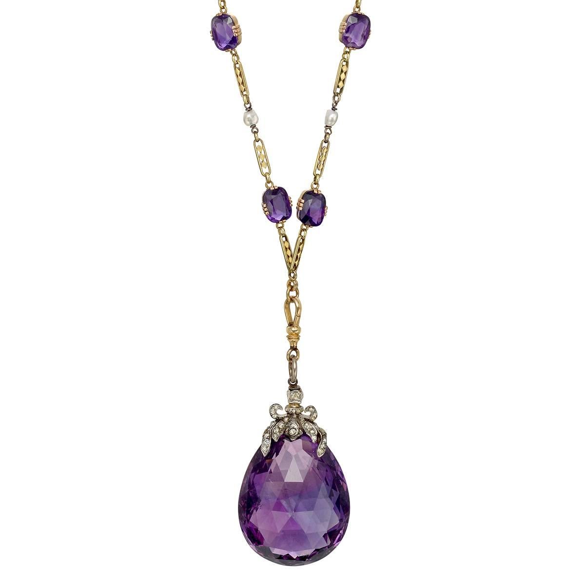 Antique Russian long necklace, showcasing a large pear-shaped faceted amethyst pendant drop with a rose-cut diamond bow and foliate motif top, suspended from a cushion-shaped amethyst and baroque pearl fancy-link chain necklace, in 14k gold, circa