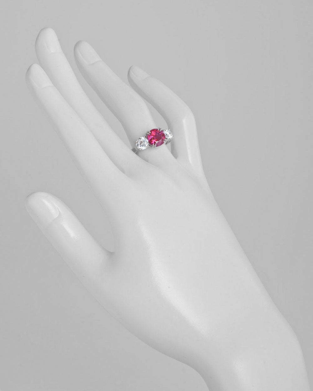 Ruby and diamond three-stone ring, centering on a round brilliant cut natural, Burmese ruby weighing 3.02 carats, with two round brilliant cut diamond shoulders weighing 1.40 total carats (both 0.70 carat with E-color/VS2-clarity), mounted in