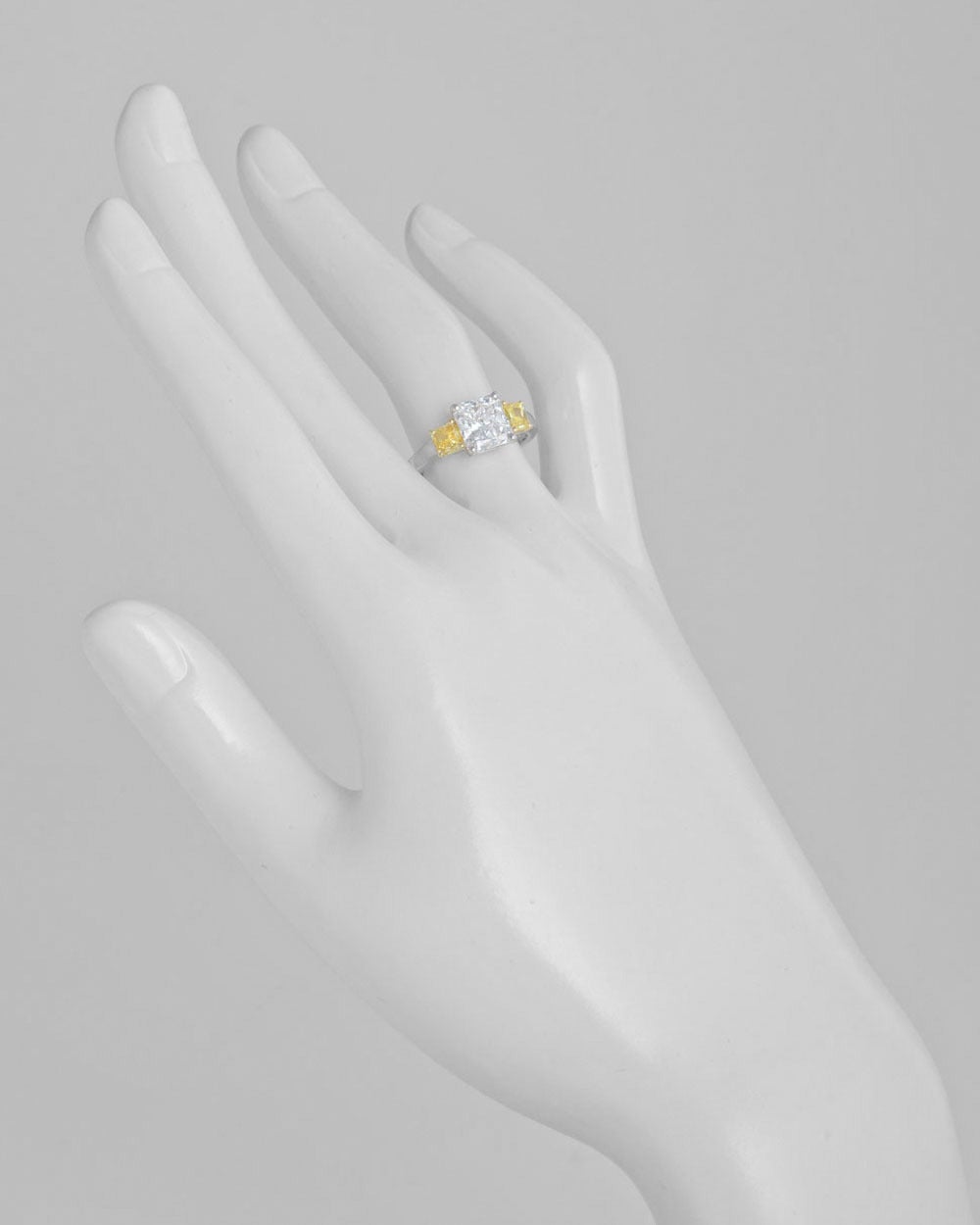 Colorless and yellow diamond three-stone engagement ring, centering on a colorless radiant-cut diamond weighing 2.05 carats (E-color/VS2-clarity), flanked by two natural, fancy intense yellow radiant-cut diamond shoulders weighing 0.34 and 0.38