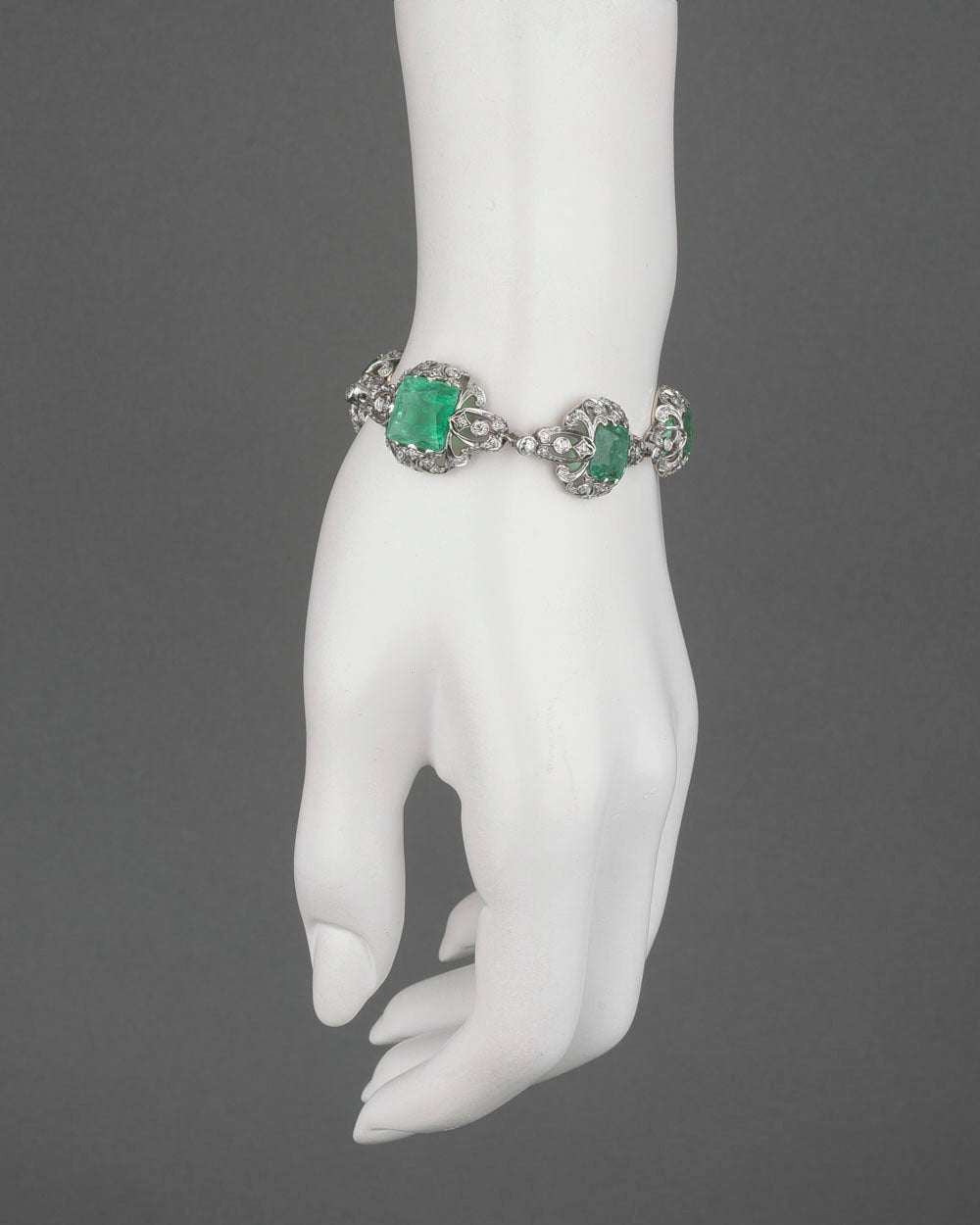 Antique emerald and diamond bracelet, set with six cushion-shaped emeralds of graduated size, the emeralds weighing approximately 20.37 total carats, accented by circular-cut diamonds weighing approximately 3.95 total carats, in a fine, pierced