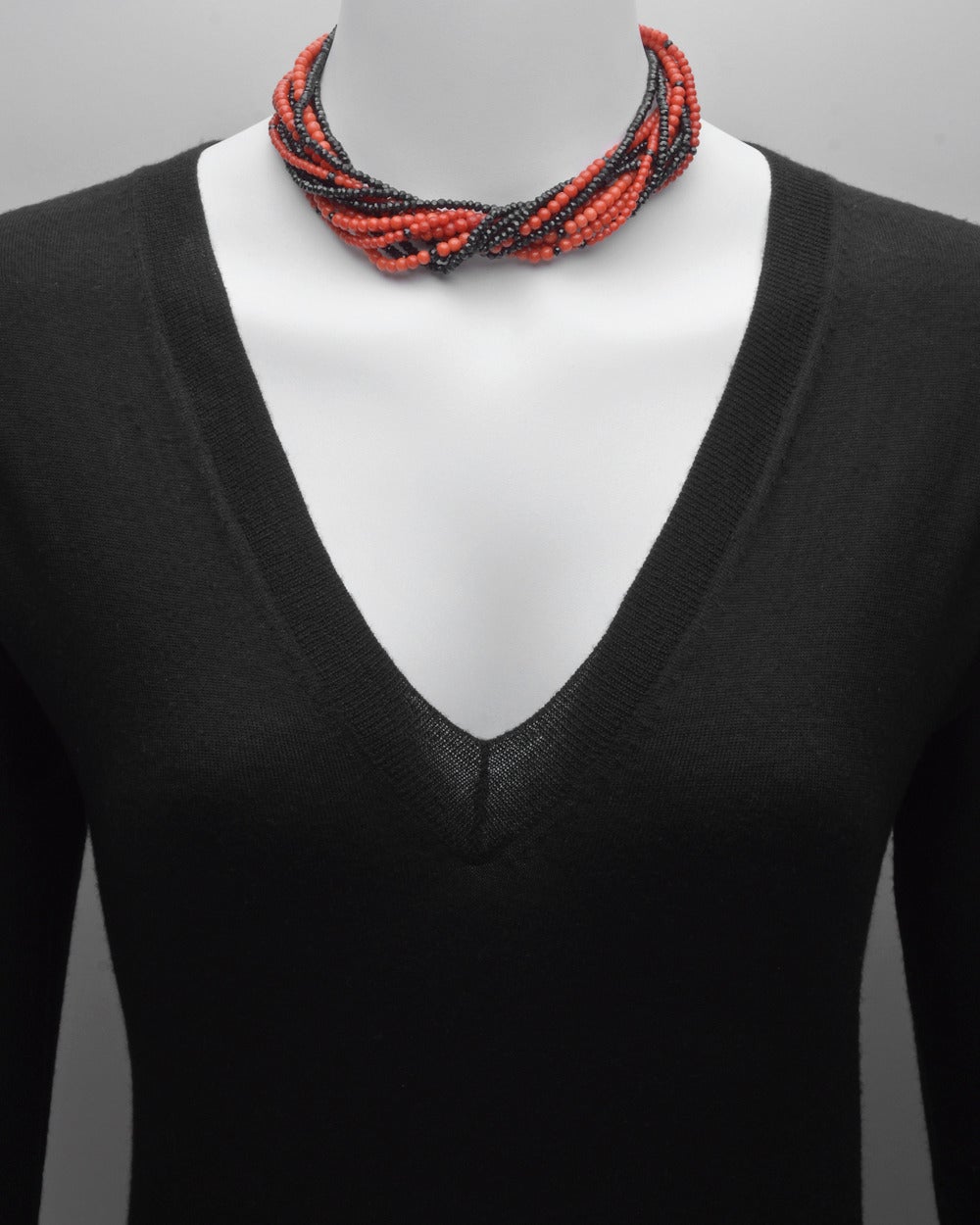 11-strand red coral and black spinel bead torsade necklace, secured by a Deco-style panel clasp in platinum accented by three circular-cut diamonds. 16