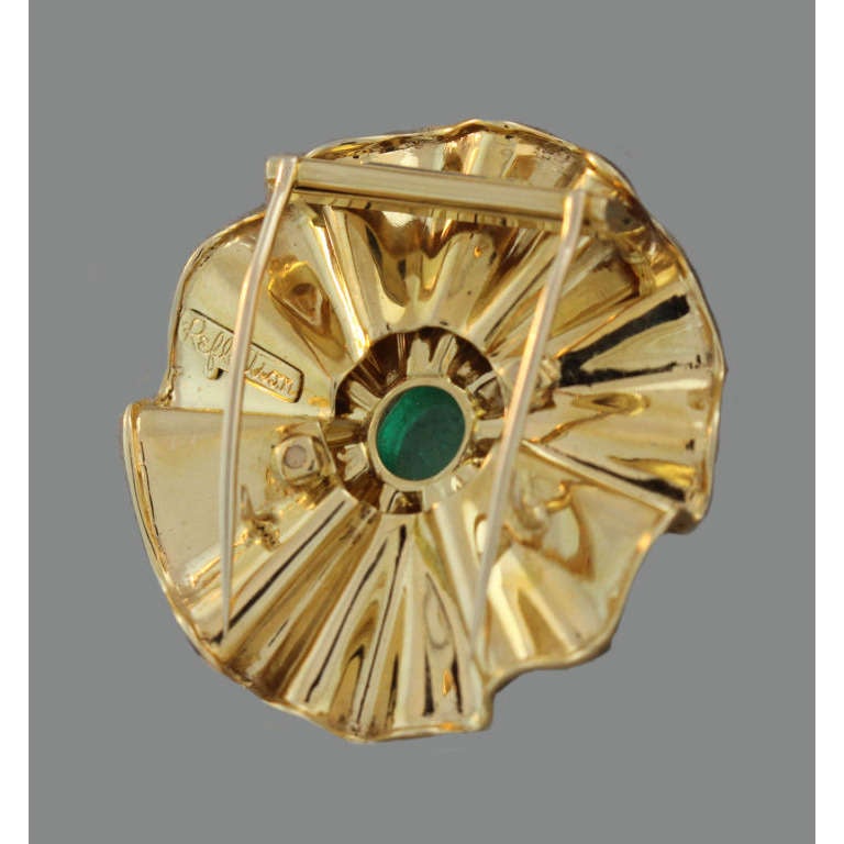 From the famous customized “Reflections” line created when Trabert & Hoeffer merged with Mauboussin, this retro brooch centers upon a cabochon-cut emerald within two “ruffled” layers of polished 14k yellow gold, with a two-pronged pin backing, circa