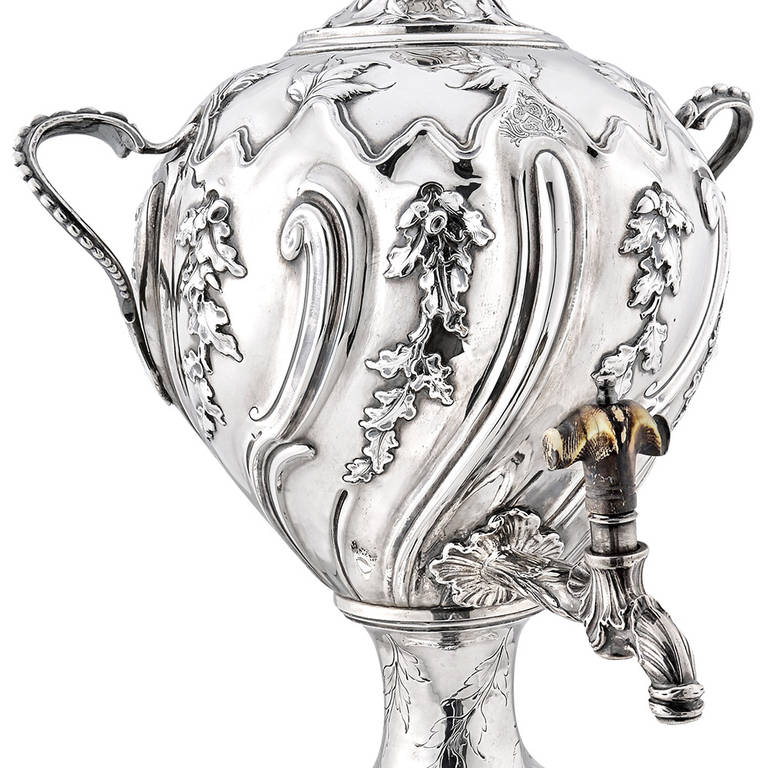 George III tea urn in sterling silver, the body designed with dense oak leaf and acorn bands and ribbed swirls, the front with engraved heraldic device depicting a rampant lion, as well as an engraved foraging squirrel at top, the removable domed