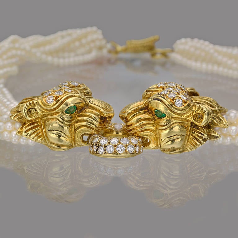 14-strand seed pearl torsade necklace, with two pavé-set diamond and yellow gold lion head motifs at center connected by a diamond-set yellow gold ring, with 68 full-cut round diamonds weighing approximately 4.10 total carats and each lion motif