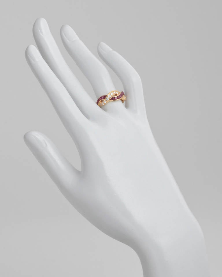 Ruby and diamond interlaced band ring, the rubies and diamonds set approximately halfway around the band, with circular-cut diamonds weighing approximately 0.60 total carats and square-cut rubies weighing 0.95 total carats, mounted in 18k yellow