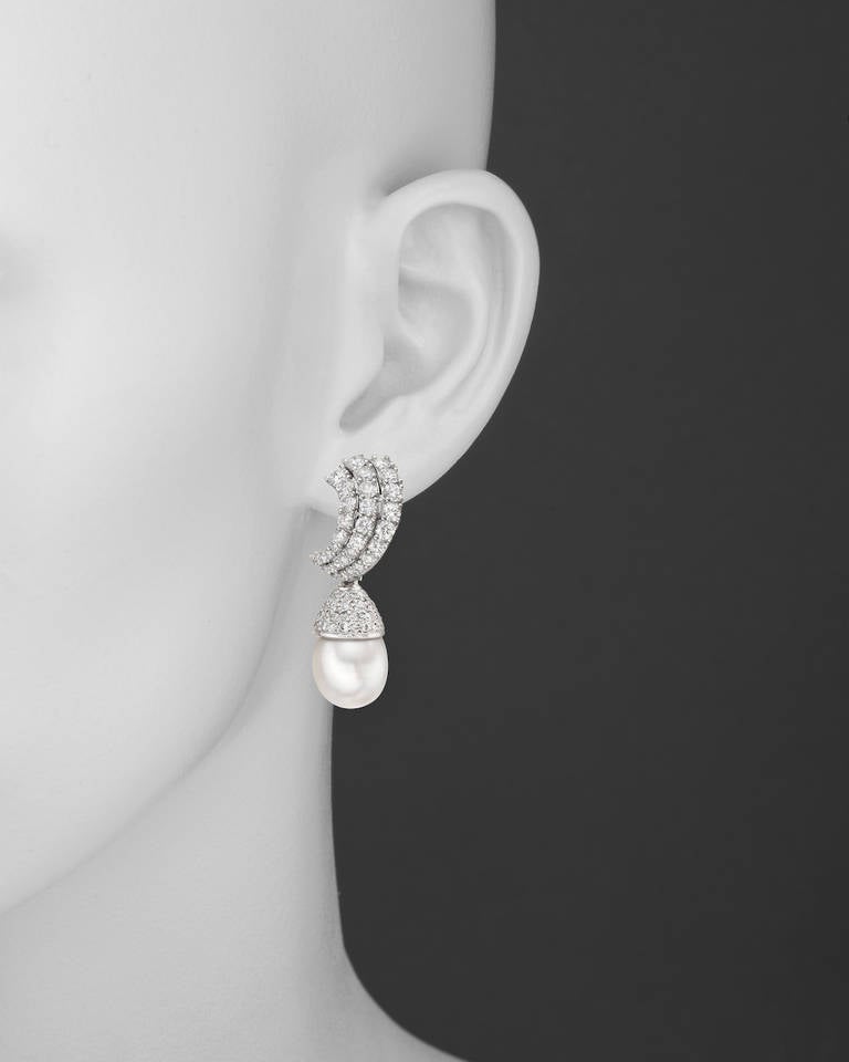 South Sea pearl and diamond drop earclips, composed of a cultured South Sea pearl drop with a pavé diamond-set cap, the cap set with 80 diamonds weighing approximately 1.72 total carats, suspended from a three-row diamond-set graduated curving top,