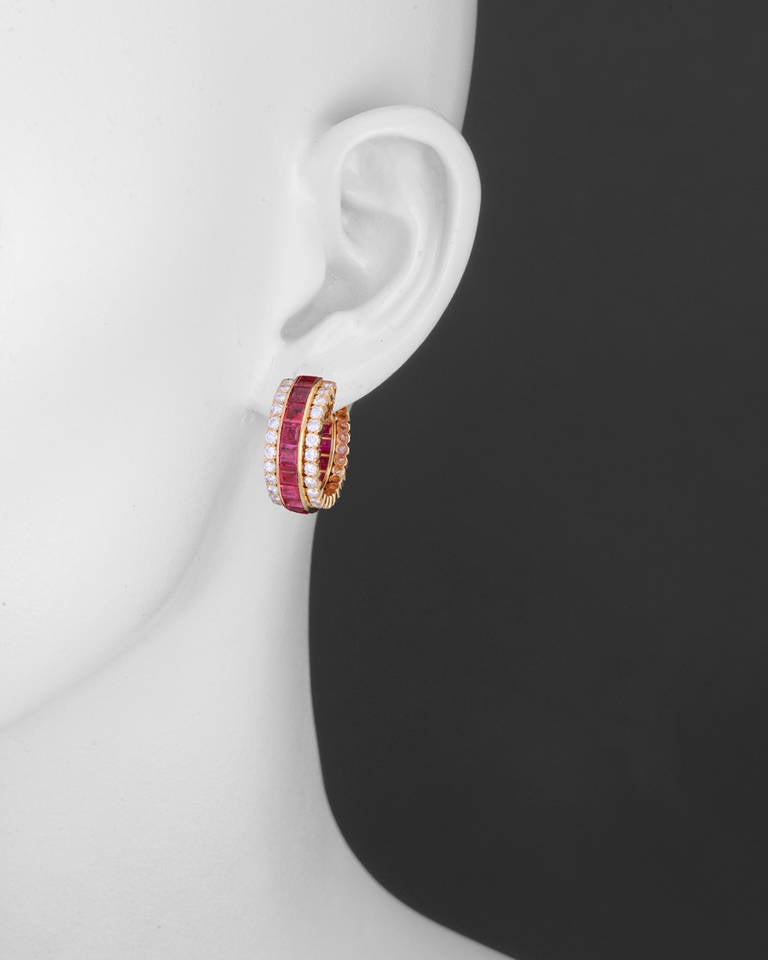 Ruby and diamond hoop earclips, designed with a central row of invisble-set square-cut rubies, flanked on either side by round-cut diamonds, mounted in 18k yellow gold, with clip backs, numbered NY46842, signed 