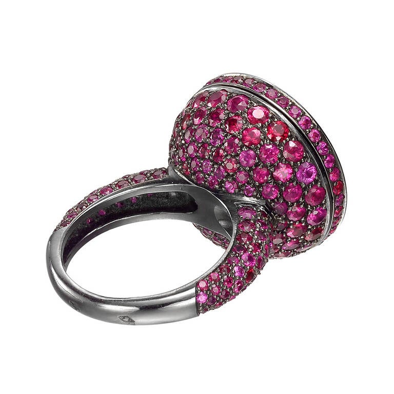 Known as a Secret or Poison ring, this ring features an innovative rotating flat disc-shaped top that opens to reveal a hidden compartment, the top, profile and shoulders of the band pavé-set with 270 circular-cut rubies weighing approximately 6.93