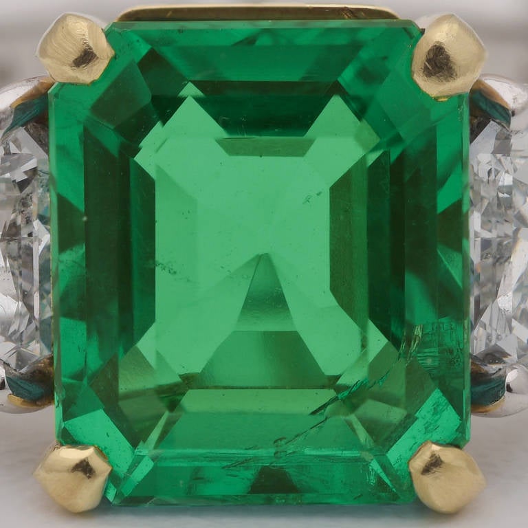 Colombian emerald and diamond dress ring, centering on an octagonal-shaped step-cut emerald weighing 3.41 carats, flanked by two calf head-shaped diamond shoulders, mounted in platinum with an 18k yellow gold central basket, signed Fred Leighton.