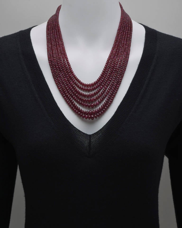 Graduated ruby bead necklace, the necklace composed of seven strands of polished ruby beads, the rubies weighing approximately 832 total carats, with a yellow gold hook clasp, the strands ranging from 19