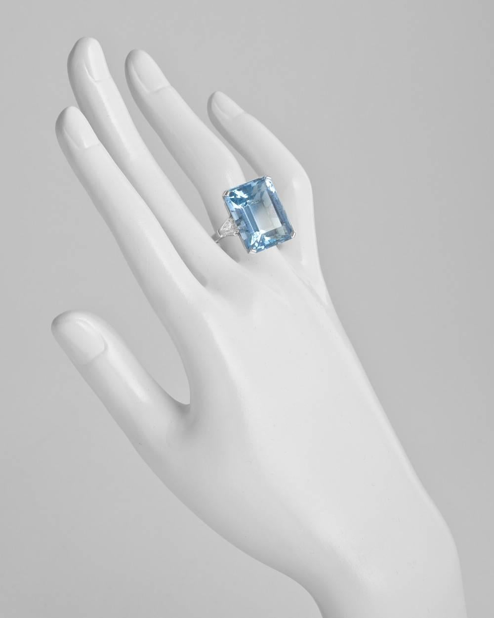Aquamarine cocktail ring, centering a finely-colored step-cut aquamarine weighing 24.07 carats and measuring approximately 20 x 16mm, flanked by a pair of colorless shield-cut diamond shoulders weighing 1.52 total carats (both F-color), mounted in