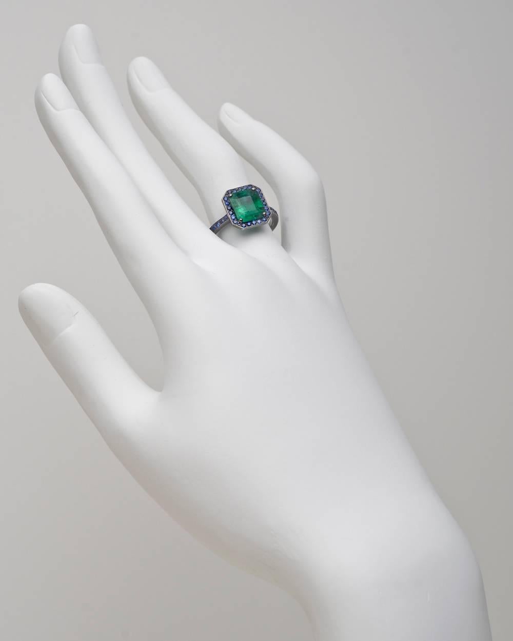 Colombian emerald ring, centering a fine octagonal-shaped emerald-cut emerald weighing 2.45 carats, with a pavé sapphire surround and partway pavé sapphire band consisting of 54 sapphires weighing 0.54 total carats, mounted in blackened 18k white