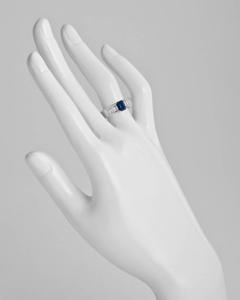 Sapphire and diamond ring, centering an emerald-cut sapphire weighing approximately 1.00 carat, with step-cut diamond shoulders and profile, the 18 diamonds weighing approximately 2.00 total carats, mounted in 18k white gold, numbered 9687870,